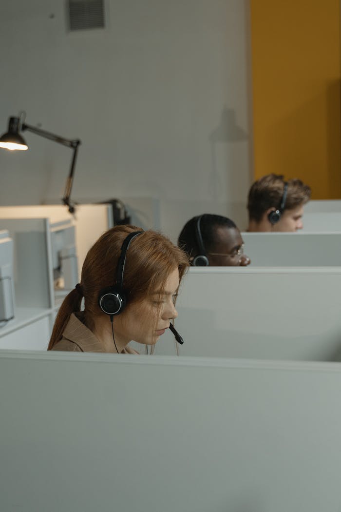 Diverse call center agents focused on their tasks in a modern workspace with headsets.